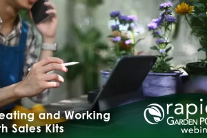 A man uses a tablet to create a sales kit within the robust Rapid Garden POS software in a garden retail setting. He is holding a pen and speaking on a phone while looking at a tablet. Surrounding them are colorful potted plants. Text: "Creating and Working with Sales Kits" -- a Rapid Garden POS webinar