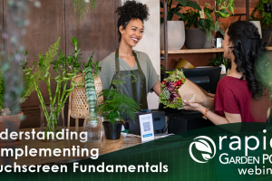 A smiling florist in an apron hands a bouquet of flowers to a customer at a counter. Various plants and flowers are displayed around them. Text: “Understanding & Implementing Touchscreen Fundamentals -- a Rapid Garden POS webinar