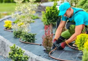 Man with Garden Gloves Kneeling Down Fixing a Hose