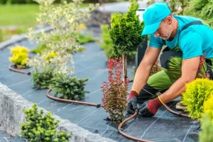 Man with Garden Gloves Kneeling Down Fixing a Hose