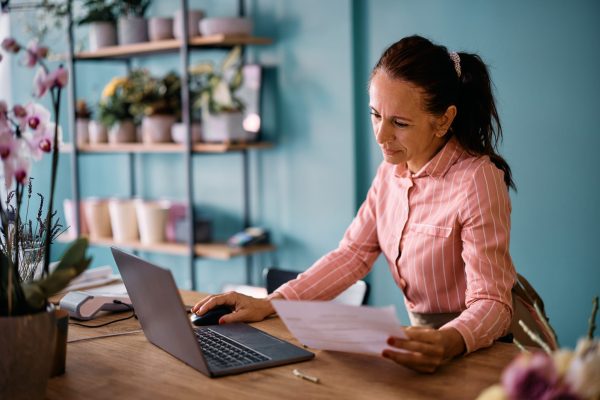 Mature flower shop owner working on a laptop and managing her accounting.