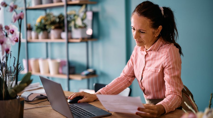 Mature flower shop owner working on a laptop and managing her accounting.