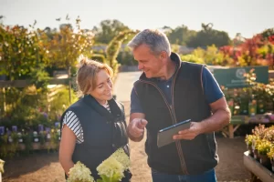 Garden center owner helping customer with a tablet, offering product selection and loyalty programs