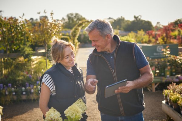 Garden center owner helping customer with a tablet, offering product selection and loyalty programs