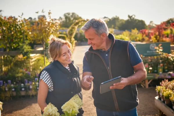 Garden center owner helping customer with a tablet, offering product selection and loyalty programs
