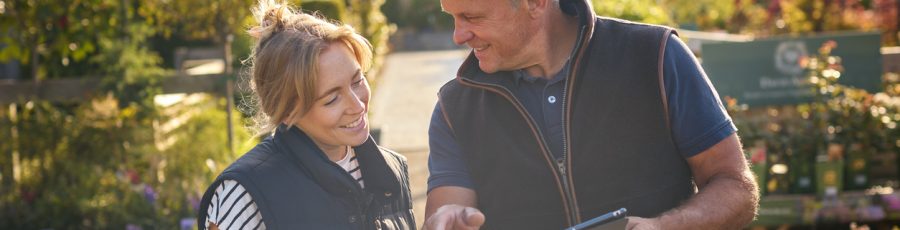 Garden center owner helping customer with a tablet, offering product selection and loyalty programs