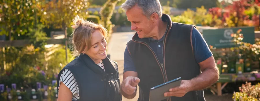 Garden center owner helping customer with a tablet, offering product selection and loyalty programs