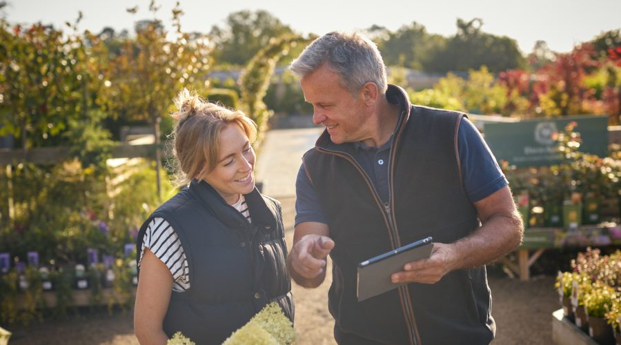 Garden center owner helping customer with a tablet, offering product selection and loyalty programs