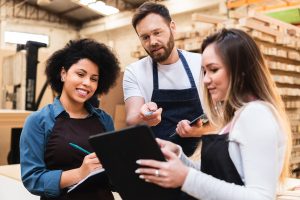 Male employee communicating changes for inventory management on a tablet in a backroom.