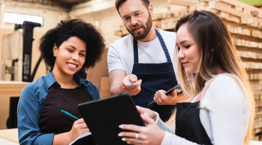 Male employee communicating changes for inventory management on a tablet in a backroom.