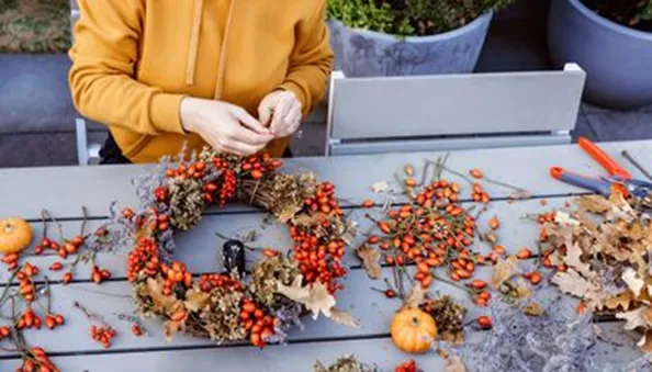 Woman Making an Autumn Wreath on a Garden Table